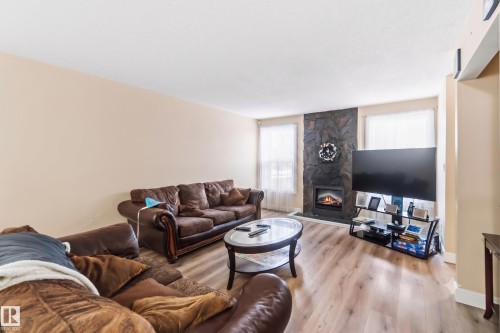 Living area featuring light wood-finish flooring and a stone-clad fireplace - 17118 108 Street, Edmonton, AB 