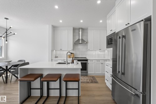 Modern kitchen featuring white shaker cabinetry and a large island with white countertops - 20907 131 Avenue, Edmonton, AB 