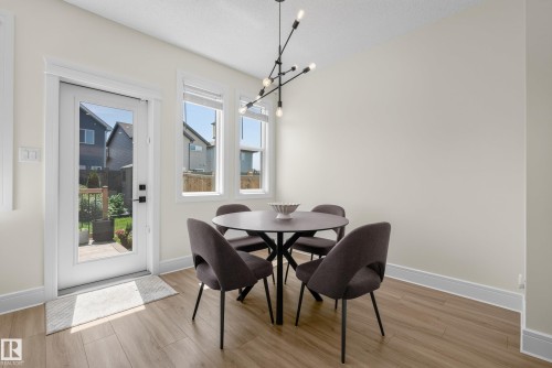 Dining area featuring wood-finish flooring, white baseboards, and a contemporary chandelier - 20907 131 Avenue, Edmonton, AB 