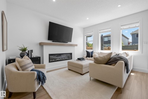 Bright living space featuring a contemporary fireplace with a light wood mantel - 20907 131 Avenue, Edmonton, AB 