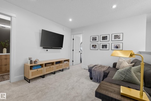 Carpeted bonus room featuring recessed lighting, a mounted flat-screen television, light-toned built-in cabinetry, and crisp white trim - 20907 131 Avenue, Edmonton, AB 