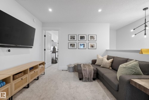 Carpeted entertainment area featuring recessed lighting, a contemporary chandelier, and a low wall partition - 20907 131 Avenue, Edmonton, AB 