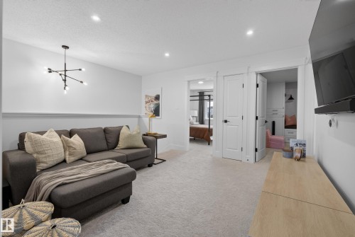 Carpeted room featuring a contemporary chandelier, recessed lighting, and white baseboards - 20907 131 Avenue, Edmonton, AB 