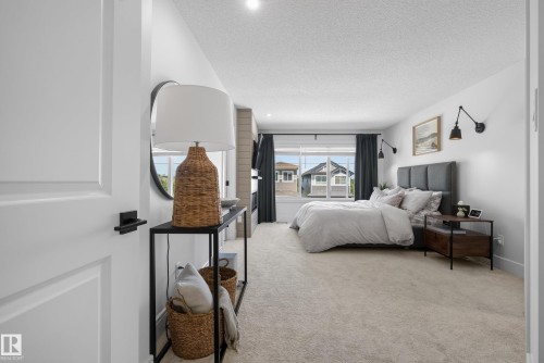 Expansive bedroom featuring neutral carpeting, a large window, and light-toned walls - 20907 131 Avenue, Edmonton, AB 