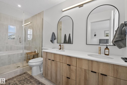 Dual vanity featuring light wood-finish cabinetry, white countertops, and arched mirrors - 20907 131 Avenue, Edmonton, AB 