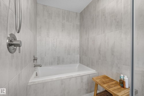 Tiled bath and shower combination featuring a built-in tub, brushed nickel fixtures, and a glass enclosure - 20907 131 Avenue, Edmonton, AB 