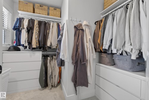 Custom closet organization system featuring multiple hanging rods, integrated drawer storage, and upper shelving - 20907 131 Avenue, Edmonton, AB 