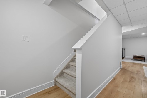 Carpeted staircase with white balustrade and trim, complemented by light wood-finish flooring - 20907 131 Avenue, Edmonton, AB 