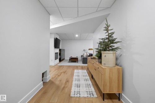 Finished entertainment area featuring wood-finish flooring, recessed lighting, and a built-in fireplace - 20907 131 Avenue, Edmonton, AB 