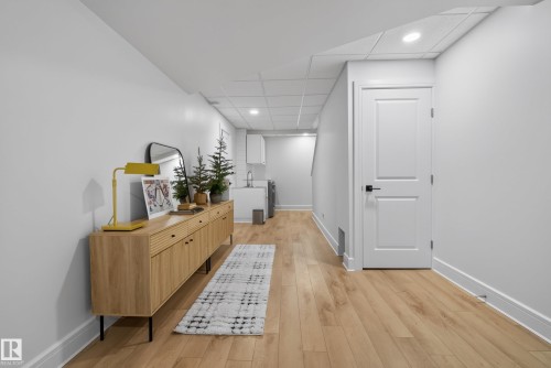 Finished lower level featuring light wood-finish flooring, recessed lighting, white trim, and a utility sink area - 20907 131 Avenue, Edmonton, AB 