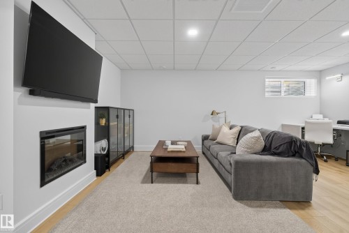 Living area featuring a wall-mounted electric fireplace, light-toned wood-finish flooring, and recessed lighting - 20907 131 Avenue, Edmonton, AB 