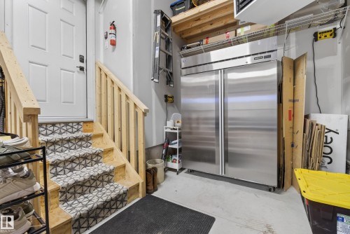 Staircase with patterned runner, wood railings, and a solid white door - 20907 131 Avenue, Edmonton, AB 