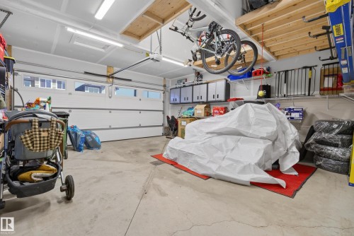 Attached two-car garage featuring a white sectional door with upper window inserts, concrete flooring, and overhead lighting - 20907 131 Avenue, Edmonton, AB 