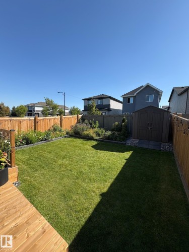 Expansive backyard featuring a natural wood deck, a manicured lawn, established garden beds, a storage shed, and full wood fencing - 20907 131 Avenue, Edmonton, AB 
