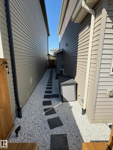 Side yard featuring a gravel pathway with square stepping stones, bordered by siding exteriors - 20907 131 Avenue, Edmonton, AB 