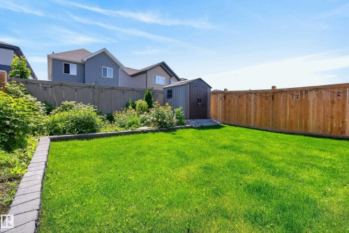 Expansive backyard featuring a lush green lawn, paver stone border, and mature landscaping - 20907 131 Avenue, Edmonton, AB 