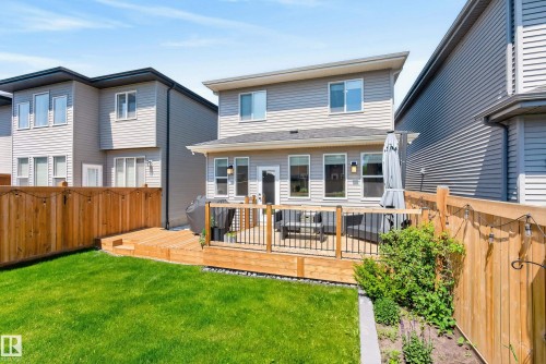 Expansive backyard featuring a manicured lawn, a multi-level wooden deck with black metal railings, and a wooden privacy fence - 20907 131 Avenue, Edmonton, AB 