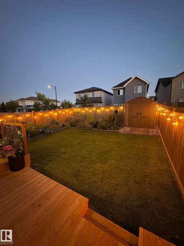 Expansive backyard featuring a natural wood deck, manicured lawn, and garden beds - 20907 131 Avenue, Edmonton, AB 