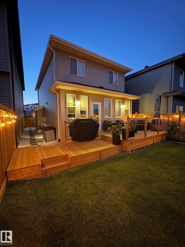 Expansive backyard featuring a multi-level wood-finish deck with integrated steps, a manicured lawn, and a fenced perimeter - 20907 131 Avenue, Edmonton, AB 