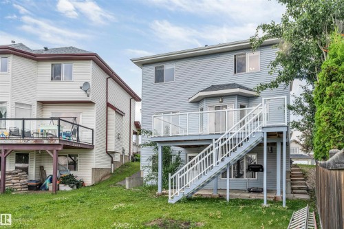 Rear exterior featuring a multi-level deck with glass panel railings, a bay window, and light blue siding - 3449 28 Street, Edmonton, AB 