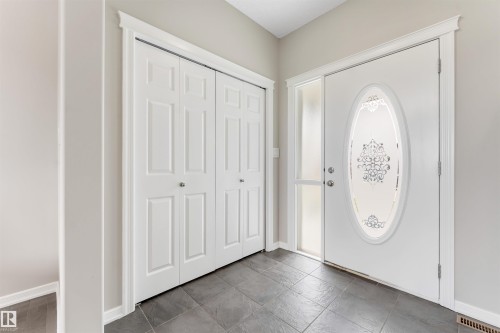 Entryway featuring a white paneled door with an oval frosted glass insert, a full-length frosted sidelight, and crown molding trim - 3449 28 Street, Edmonton, AB 