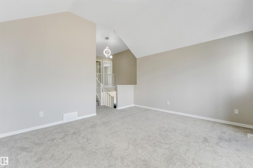 Spacious room featuring vaulted ceilings, light gray wall paint, and light gray carpeted flooring - 3449 28 Street, Edmonton, AB 