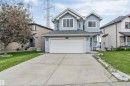 Light blue siding exterior featuring a multi-pane window configuration, attached garage, concrete driveway, and front entry porch with white railings - 3449 28 Street, Edmonton, AB 