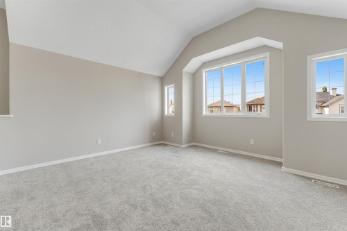 Vaulted ceilings enhance this room featuring light gray carpeting and neutral wall tones - 3449 28 Street, Edmonton, AB 
