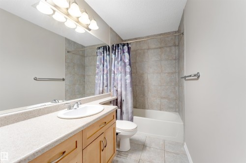 Bathroom featuring a built-in vanity with wood-finish cabinetry, an integrated sink, and a light-colored countertop - 3449 28 Street, Edmonton, AB 