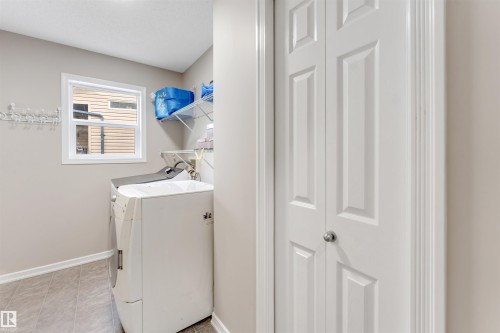 Dedicated laundry area featuring a window, built-in shelving, and a wall-mounted drying rack - 3449 28 Street, Edmonton, AB 