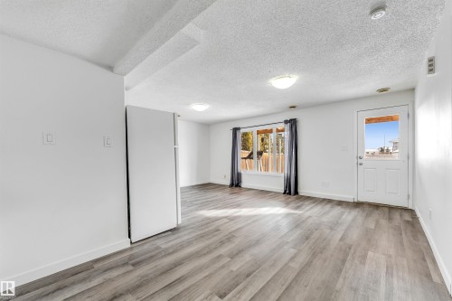 Open-concept room featuring wood-finish flooring, white walls, and a white refrigerator - 3449 28 Street, Edmonton, AB 