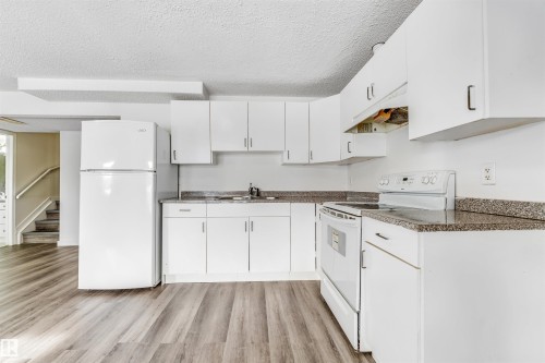 Kitchen featuring white cabinetry, laminate countertops, a white refrigerator, and a white electric range - 3449 28 Street, Edmonton, AB 