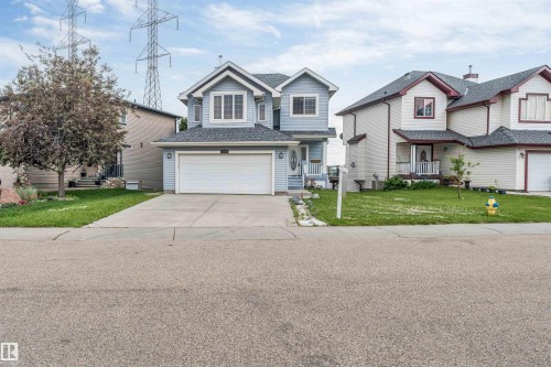 Two-story residence featuring light blue siding with white trim, a dark shingled roof, and an attached two-car garage - 3449 28 Street, Edmonton, AB 