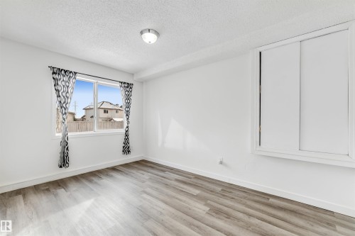 An empty room featuring a window with a white frame, wood-finish flooring, and white walls - 3449 28 Street, Edmonton, AB 
