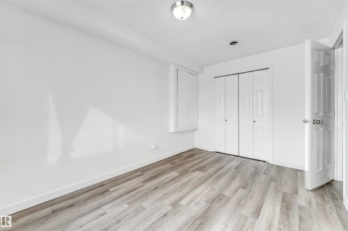 Room featuring wood-finish flooring, white walls, and a white bi-fold closet - 3449 28 Street, Edmonton, AB 