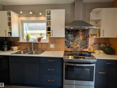 Modern kitchen featuring white upper cabinetry, dark lower cabinetry, and a contemporary backsplash with a unique marbled pattern. - 4806 50 Avenue, Elk Point, AB 