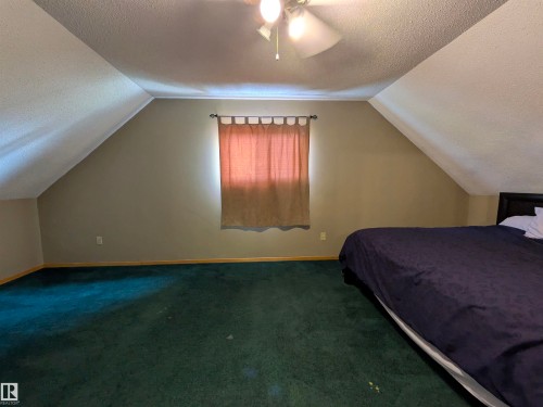 Room featuring a ceiling fan, window with curtains, and sloped ceilings. - 4806 50 Avenue, Elk Point, AB 