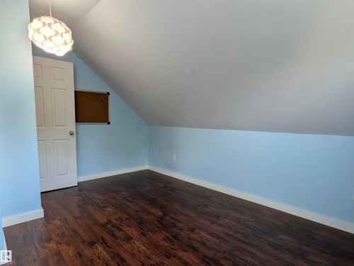 Room featuring wood-finish flooring, light blue walls, and a white angled ceiling. - 4806 50 Avenue, Elk Point, AB 