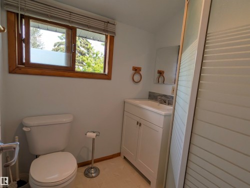 Bathroom featuring a white vanity with integrated sink, chrome faucet, and a tiled backsplash. - 4806 50 Avenue, Elk Point, AB 