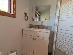 Bathroom vanity featuring a white cabinet with brushed nickel hardware, an integrated sink, a light-toned countertop, and a gray-toned tile backsplash. - 