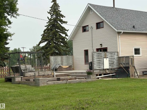 Expansive backyard featuring a multi-level wooden deck with privacy fencing, integrated raised garden beds, and a swing set structure. - 4806 50 Avenue, Elk Point, AB 