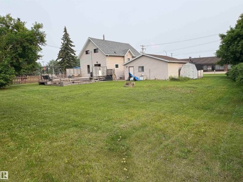 Expansive lawn with  residence, a detached garage, and a shed. - 4806 50 Avenue, Elk Point, AB 