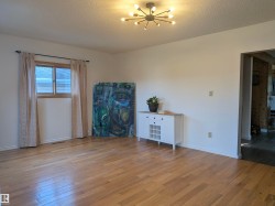 Bright interior space featuring wood-finish flooring, a contemporary ceiling light fixture, and a window with trim. - 