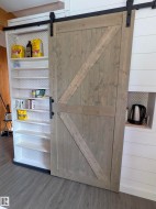 Sliding barn door with dark hardware, offering access to built-in shelving. - 