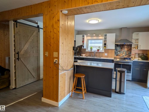 Modern kitchen with an island featuring a light-colored countertop and dark cabinetry. - 4806 50 Avenue, Elk Point, AB 