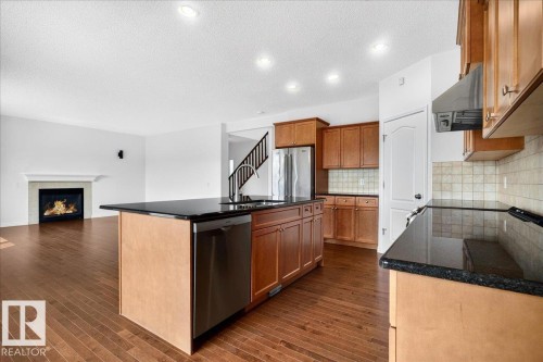 Kitchen featuring wood-finish flooring, granite countertops, wood cabinetry, and stainless steel appliances - 8508 218 Street, Edmonton, AB 