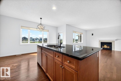 Kitchen island with dark countertop, integrated sink, and rich wood-finish cabinetry - 8508 218 Street, Edmonton, AB 