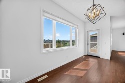 Open-concept living area with dark wood-finish flooring, white walls, and a contemporary geometric chandelier - 