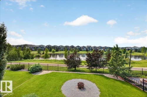 Expansive backyard with a manicured lawn, established trees, and a gravel fire pit area - 8508 218 Street, Edmonton, AB 
