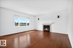 Spacious room featuring rich wood-finish flooring and a large window with roller shades - 